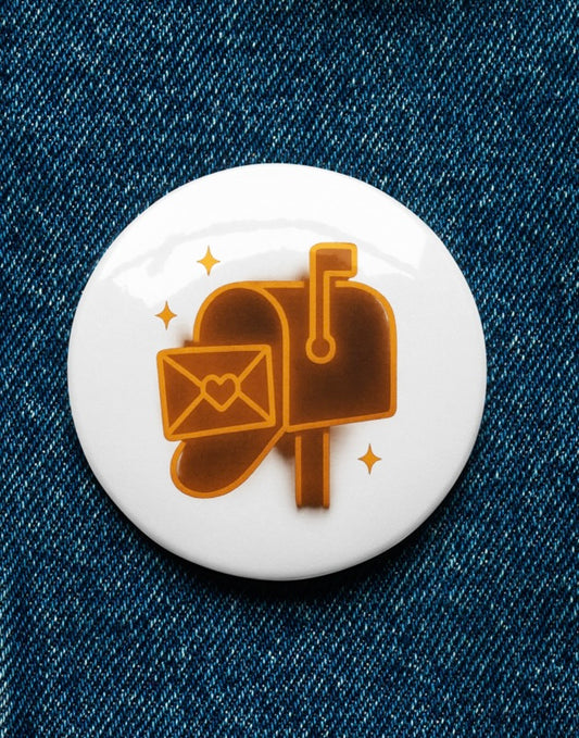 Button badge with mailbox and envelope design on a denim background